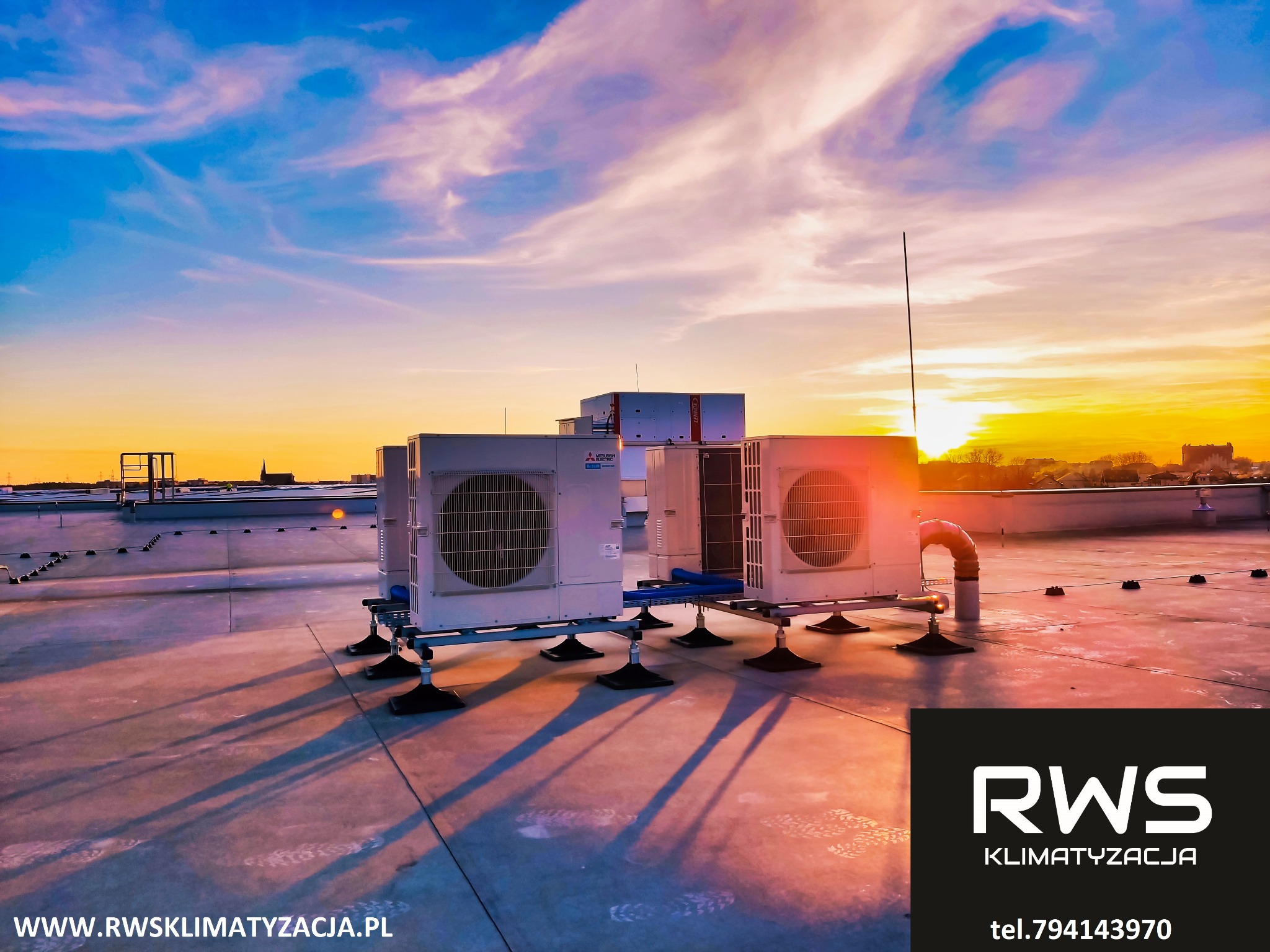 Instalacja zewnętrznych jednostek klimatyzacyjnych Mitsubishi Electric na dachu budynku, widok o zachodzie słońca.