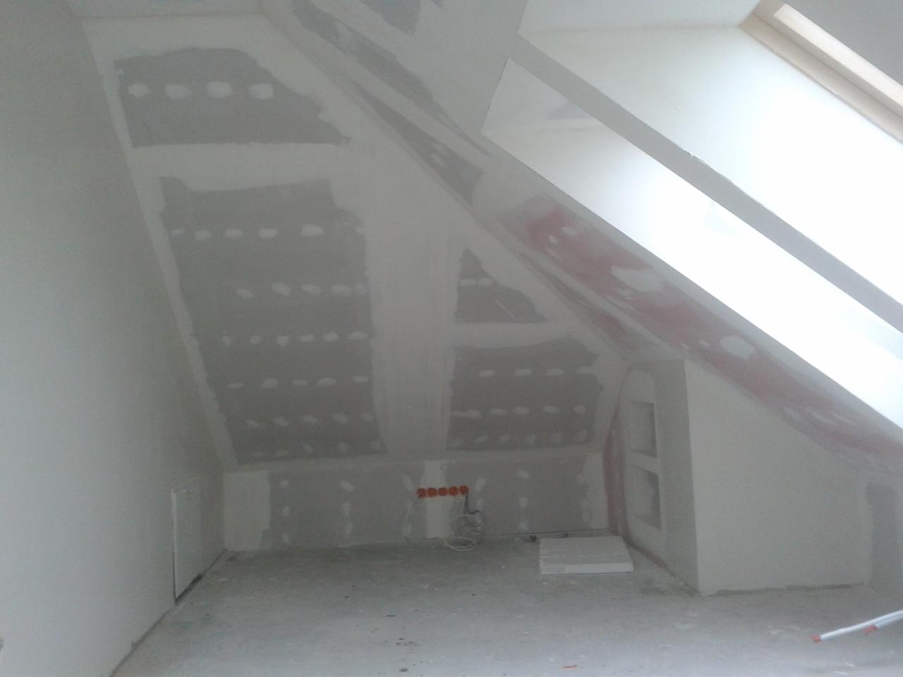 Poddasze we Wrocławiu w trakcie wykańczania: ściany i skosy pokryte płytami gipsowo-kartonowymi przed szpachlowaniem, widoczne puszki elektryczne i okno dachowe.