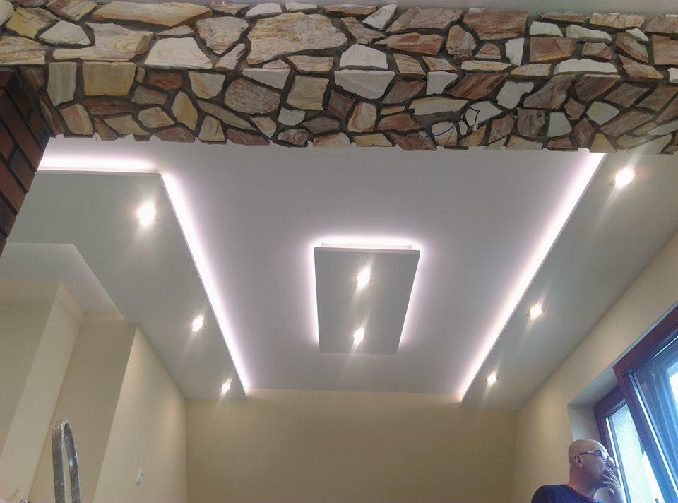 Nowoczesny sufit podwieszany z oświetleniem LED, wykończony kamienną okładziną na górnej krawędzi, widok z dołu.