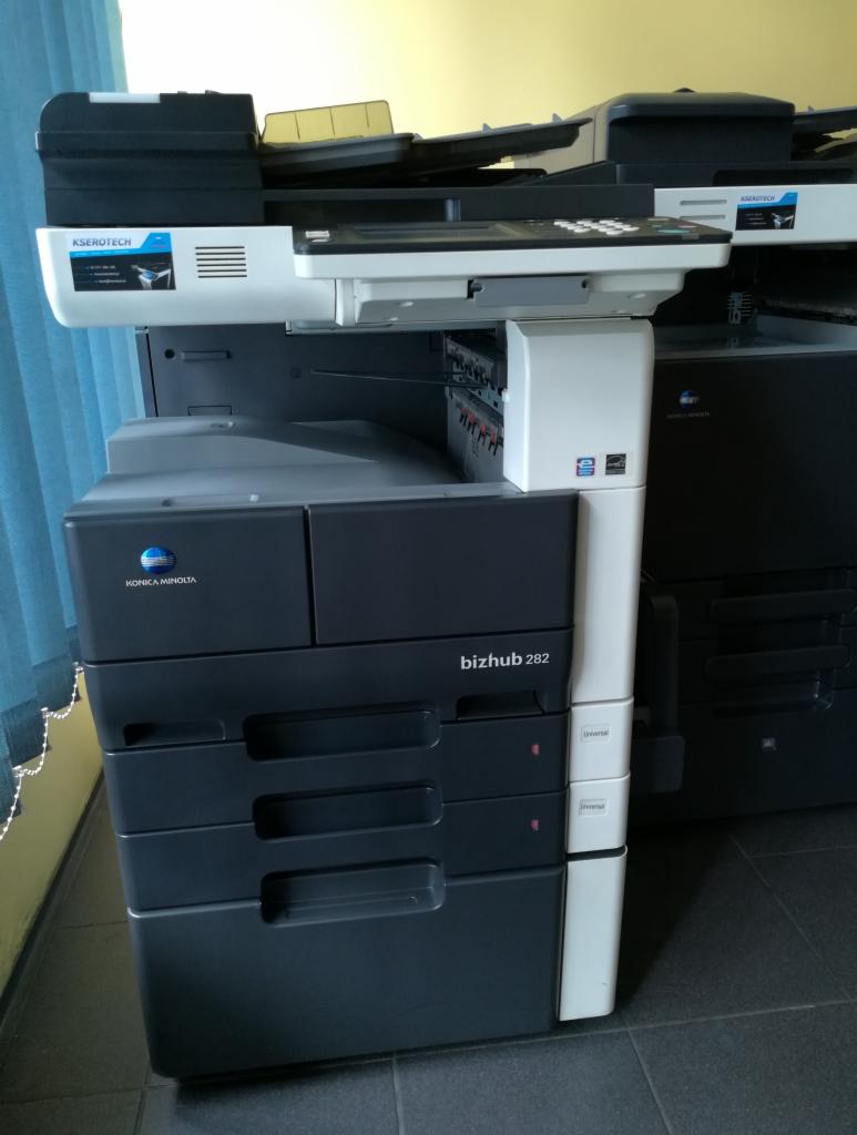 Kserokopiarka Konica Minolta bizhub 282 w kolorze czarno-białym, widoczne logo producenta i oznaczenie modelu, obok druga kserokopiarka w tle.