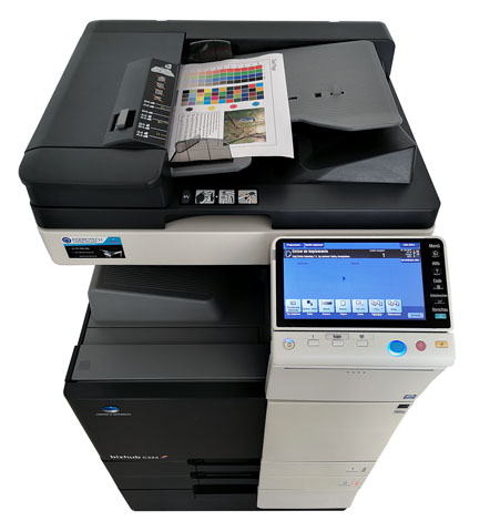 Wielofunkcyjna kserokopiarka Konica Minolta bizhub C224 z podajnikiem dokumentów i panelem dotykowym, widok z góry na białym tle. Na podajniku arkusz z kolorową kartą testową i zdjęciem krajobrazu.