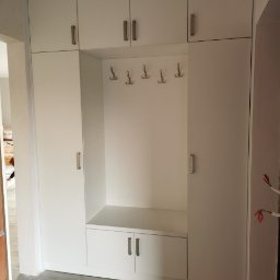 F.H.P.U.DREWMAK - Biała szafa wnękowa z siedziskiem i wieszakami, minimalistyczny design, jasne wnętrze, widok z przodu, proste uchwyty, funkcjonalne rozwiązanie do przedpokoju.