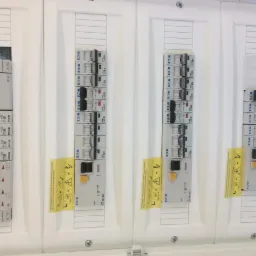 Rozdzielnia elektryczna z bezpiecznikami i wyłącznikami różnicowoprądowymi firmy Eaton, zamontowana w Pruszkowie, z widocznymi naklejkami ostrzegawczymi i oznaczeniami poszczególnych elementów.