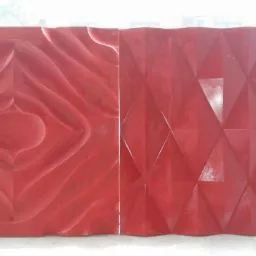 Dwa czerwone panele dekoracyjne: jeden z falistym wzorem, drugi z geometrycznym deseniem trójkątów, ustawione obok siebie na tle okna.