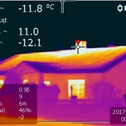 Termowizyjne zdjęcie dachu domu jednorodzinnego, ukazujące rozkład temperatur. Widoczne wartości minimalne i maksymalne temperatury oraz datę wykonania pomiaru. Dom z kominem, okno z widocznym...