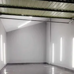 Wnętrze pomieszczenia po szpachlowaniu ścian i położeniu ciemnej, błyszczącej podłogi, widoczne pionowe lampy na ścianach.