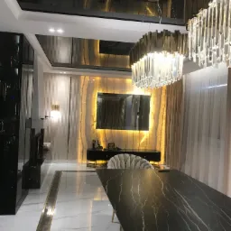 Eleganckie wnętrze jadalni z czarnym, błyszczącym sufitem, marmurową podłogą, podświetlaną ścianą z onyksu i kryształowym żyrandolem nad ciemnym stołem.