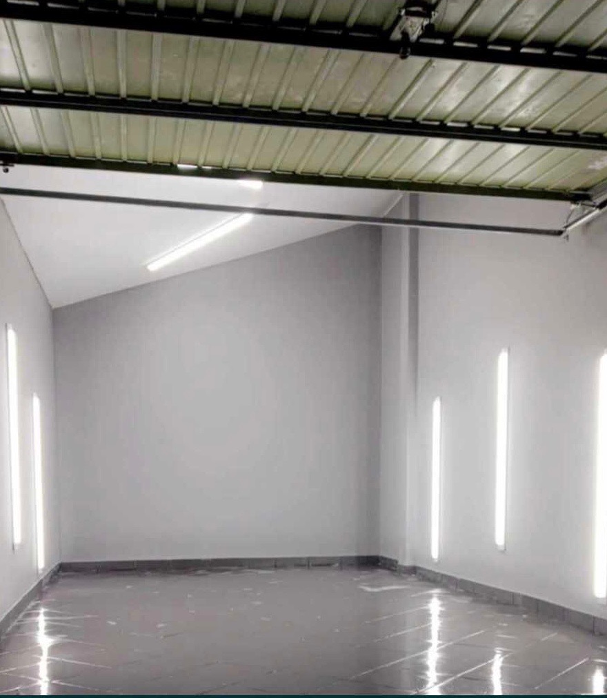 Wnętrze pomieszczenia po szpachlowaniu ścian i położeniu ciemnej, błyszczącej podłogi, widoczne pionowe lampy na ścianach.