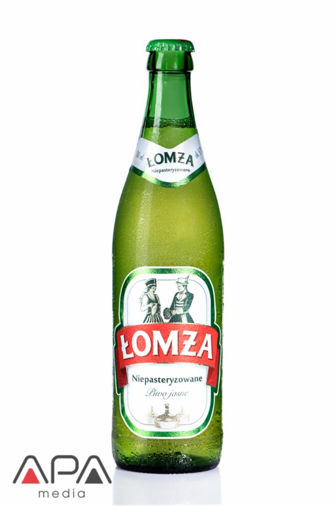 Szklana butelka niepasteryzowanego piwa jasnego Łomża, pokryta kroplami, z etykietą przedstawiającą parę w strojach ludowych, na białym tle.
