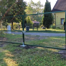 LIVBET-ECO - Ogrodzenia Systemowe - Zielona siatka ogrodzeniowa z furtką i bramą wjazdową, świeżo zamontowana na betonowej podmurówce, widok na dom i ulicę