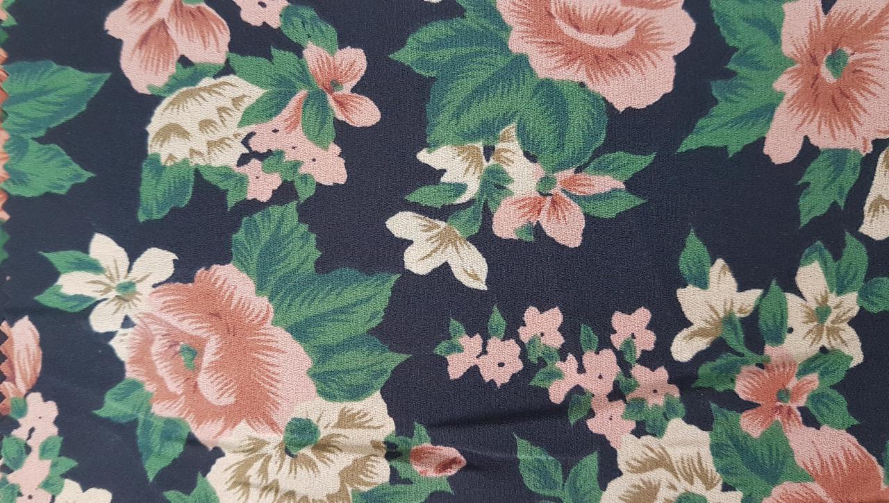 Ciemna tkanina w drobne, pastelowe róże i zielone liście, ułożone gęsto na całej powierzchni.