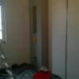 Pionowy grzejnik w zabudowie z płyt kartonowo-gipsowych, widoczny fragment okna i drabina malarska, przygotowania do malowania ścian.