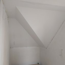 MG System - Wnętrze pokoju ze skośnym sufitem po świeżym pomalowaniu na biało, widoczne niedoskonałości i ślady po taśmie malarskiej, na podłodze fragment drabiny malarskiej.
