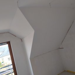 MG System - Poddasze po świeżym pomalowaniu na biało, widoczne ślady taśmy malarskiej przy suficie i oknie, przygotowane do dalszych prac wykończeniowych.