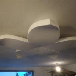 MG System - Dekoracyjny element sufitowy z białych płyt, przypominający abstrakcyjny kwiat, zamontowany w pomieszczeniu z widocznym okablowaniem i narzędziami w tle.