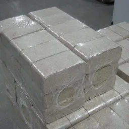 Ułożone palety brykietu drzewnego RUF owinięte folią termokurczliwą, z widocznymi otworami wentylacyjnymi w każdym bloku, na szarym betonowym podłożu.