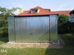 Gotowy garaż blaszany z ryflowanej blachy ocynkowanej na trawniku, w tle dom z czerwoną dachówką.