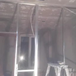 Stelaż z profili metalowych do ścianki działowej z płyty karton gips, widoczne nierówności na ścianie i suficie, przygotowanie do montażu okładzin.