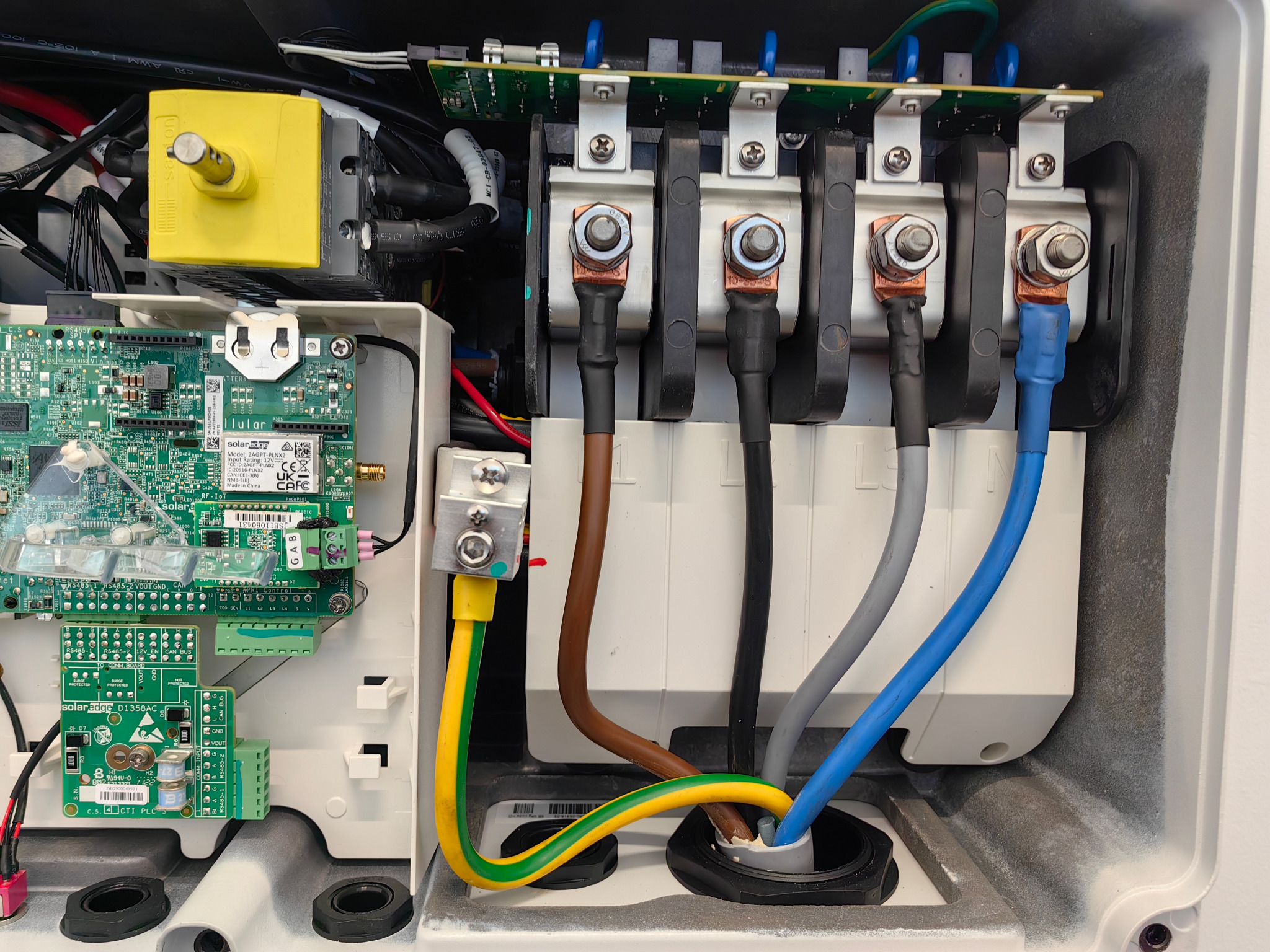 Szczegółowe ujęcie instalacji elektrycznej w Sławie, z widocznymi przewodami o różnych kolorach, podłączonymi do złączek. Widoczne elementy elektroniki i płyty PCB.
