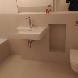 Fliziarz.pl OTTO HAJDUK - Nowoczesna łazienka w beżowych odcieniach z podwieszaną umywalką, toaletą i wanną, minimalistyczny design.