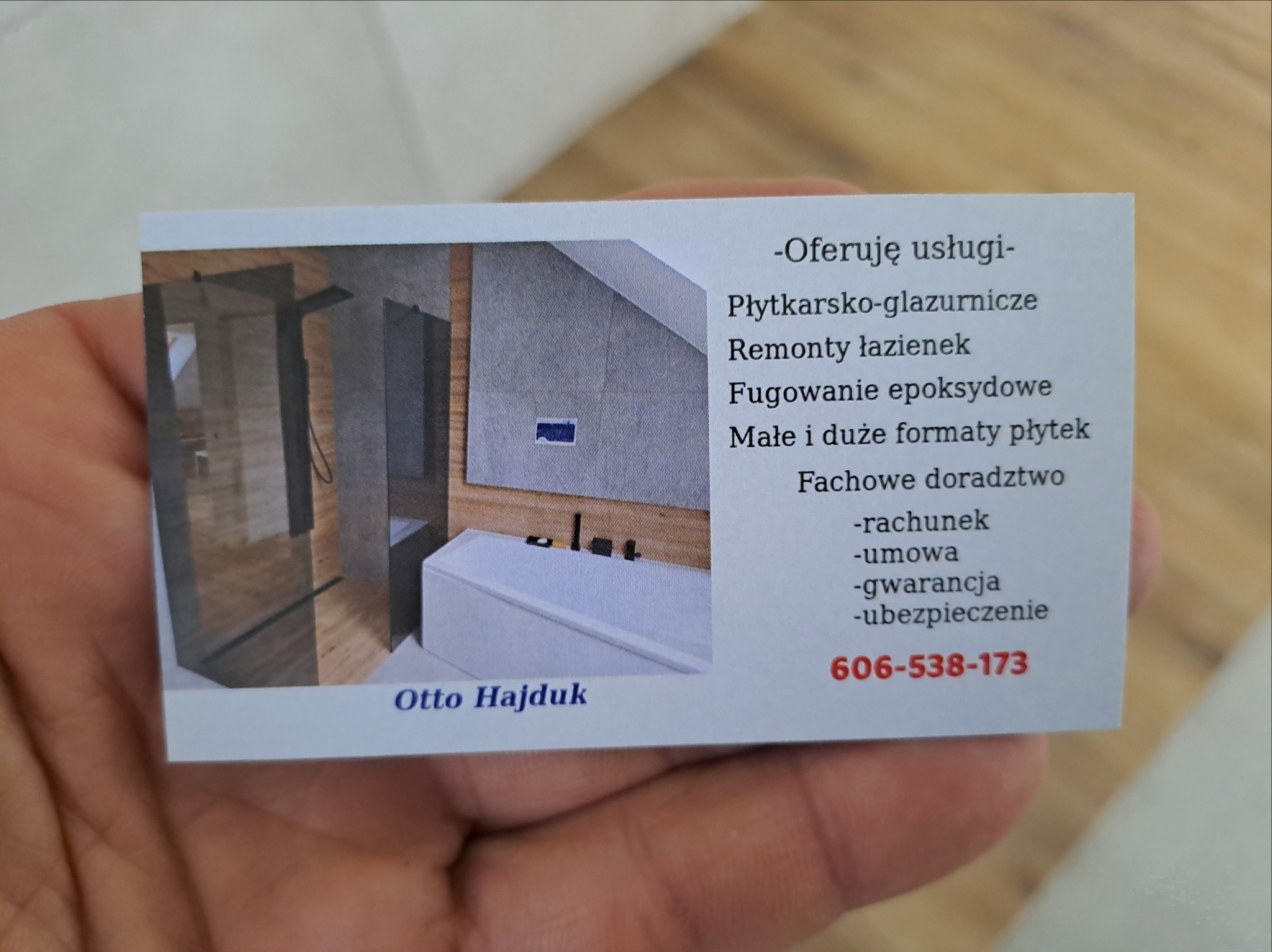 Wizytówka firmy remontowej Otto Hajduk, oferującej usługi płytkarsko-glazurnicze, remonty łazienek, fugowanie epoksydowe oraz fachowe doradztwo, z przykładowym zdjęciem łazienki w tle.