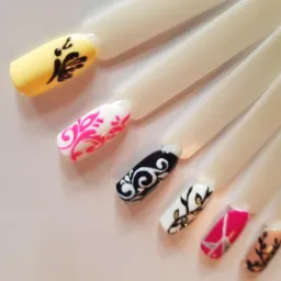 Wzornik z sześcioma sztucznymi paznokciami, każdy pomalowany innym, ozdobnym wzorem: żółty z czarnym motywem roślinnym, biały z różowym ornamentem, czarny z białymi zawijasami, biały z złotymi...