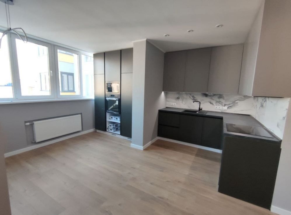 Nowoczesna kuchnia w odcieniach szarości z drewnianą podłogą, marmurowym backsplashiem i zabudowaną lodówką z piekarnikiem.