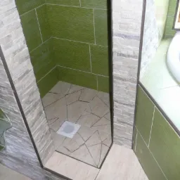 Wykończony brodzik w Jeleniej Górze z zielonymi płytkami ściennymi o subtelnej fakturze i mozaiką na podłodze, otoczony kamienną obudową.