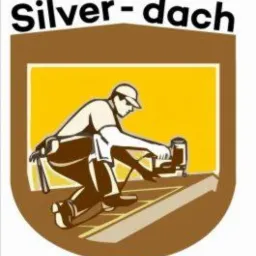 Ilustracja przedstawiająca dekarza w pracy z narzędziem na dachu, umieszczona wewnątrz brązowej tarczy z żółtym tłem i napisem 'Silver-dach' u góry.