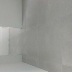 NEST BUDOWNICTWO Karol Flis - Ściany w trakcie szpachlowania, widoczne łączenia płyt gipsowo-kartonowych, surowe wykończenie, oświetlenie górne podkreśla nierówności.