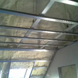 Poddasze ocieplone pianą natryskową z widoczną konstrukcją metalową pod płyty gipsowo-kartonowe, widok z dołu.