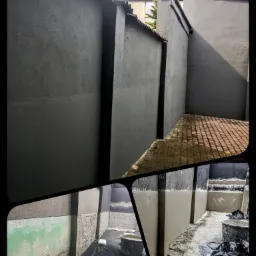 Szare ściany budynków po nałożeniu tynku, widoczne fragmenty starej elewacji i przygotowane materiały budowlane na folii. Na górze kadru widoczny fragment dachu z czerwonej dachówki.