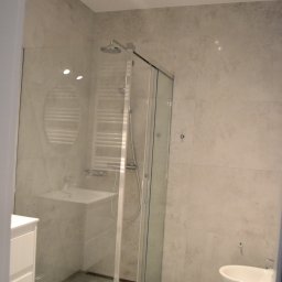 MB Constructions Michał Borkowski - Nowoczesna łazienka z kabiną prysznicową ze szklanymi drzwiami, umywalką w kabinie, grzejnikiem drabinkowym i białym bidetem z toaletą, oświetlona reflektorami punktowymi.