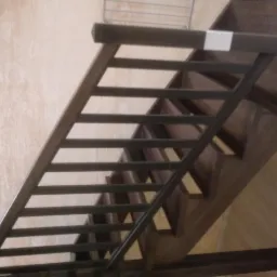 Drewniane schody z metalową balustradą w nowoczesnym stylu, widok z dołu, jasne ściany w tle.