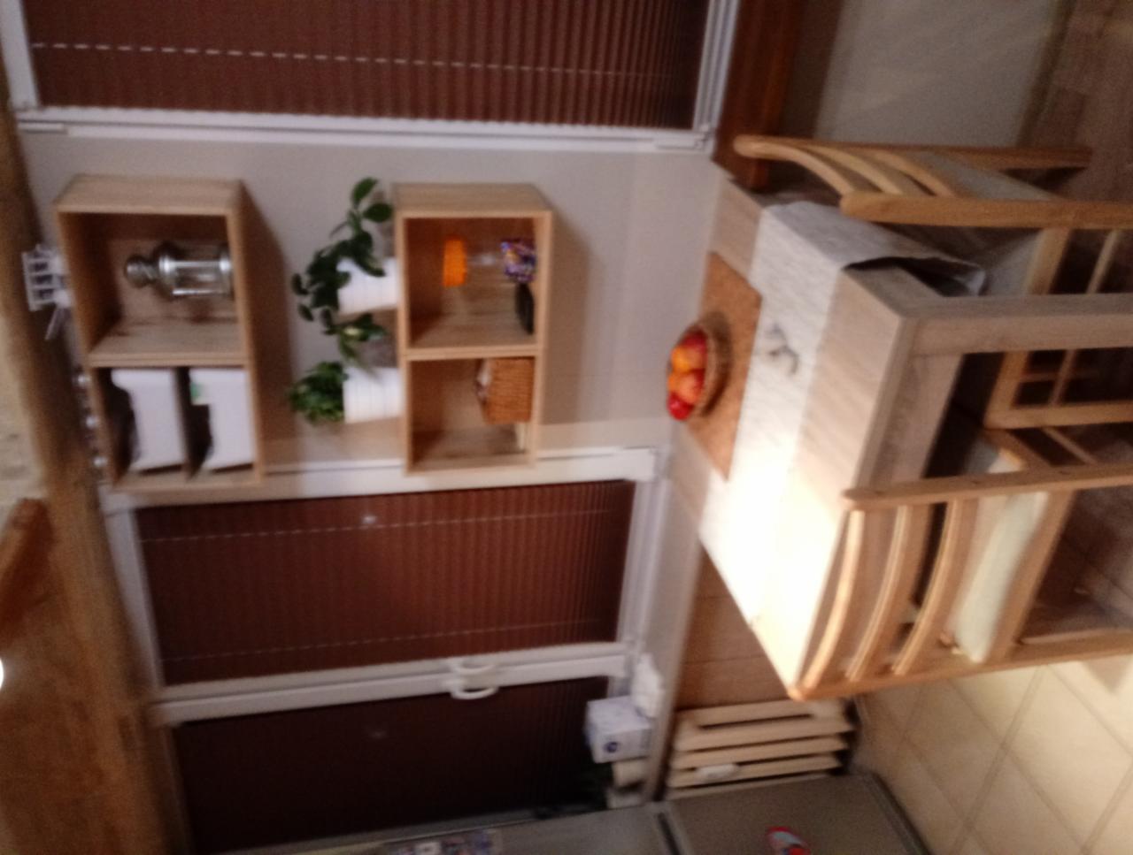 Drewniana zabudowa okienna z półkami, dekoracjami i fragmentem stołu z owocami, widok z góry.