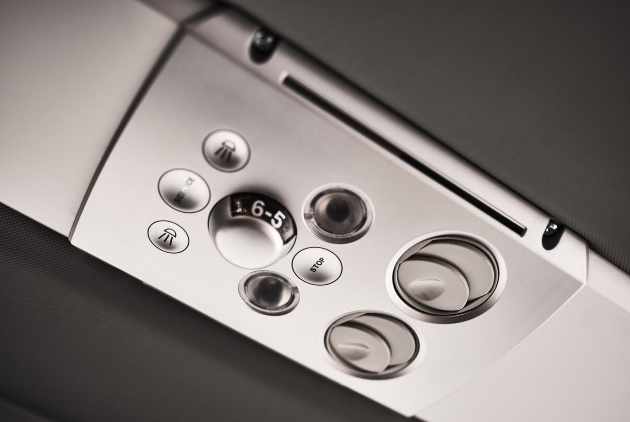 Panel sterowania wewnątrz pojazdu z oświetleniem punktowym, regulacją nawiewu i przyciskiem 'Stop', widoczne z perspektywy pasażera.