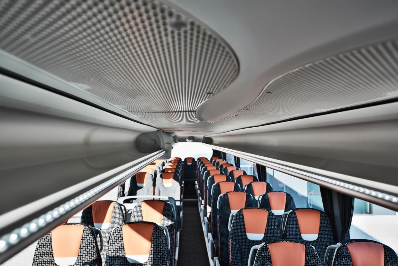 Wnętrze autobusu dalekobieżnego z rzędami foteli z pomarańczowymi zagłówkami i oświetleniem LED podsufitki