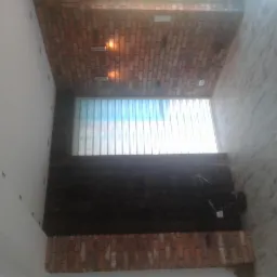 Wnętrze z ceglanym sufitem, oknem z żaluzjami i ścianą z fakturą, widok z dołu.