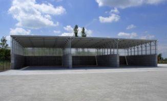 Konstrukcja hali magazynowej z prefabrykatów betonowych, widok zewnętrzny, błękitne niebo z chmurami w tle.