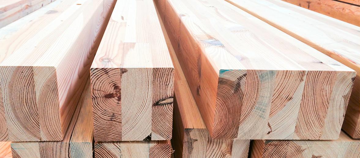 Krawędziaki z drewna klejonego warstwowo, widoczne słoje i struktura drewna, przygotowane do budowy.