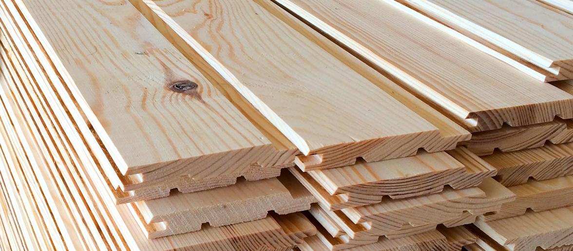 Stos jasnych, surowych desek boazeryjnych z widocznymi słojami drewna i systemem łączenia pióro-wpust.