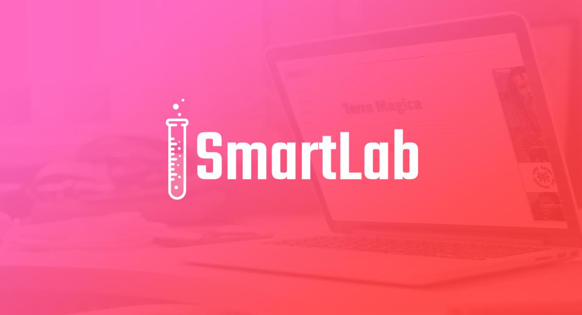 Logo firmy SmartLab na tle rozmytego ekranu laptopa z otwartą stroną internetową Terra Magica, obok stylizowana ikona probówki.