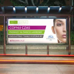 Billboard na przystanku autobusowym reklamujący zabieg endoliftingu twarzy laserem Fotona 4D w Activ Centrum, z portretem kobiety po prawej stronie i sloganem 'Cofnij czas' u g&oacute;ry, widoczne smugi...