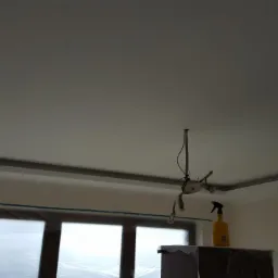 Wykończony sufit podwieszany z obniżeniem w Sidzinie, widoczne zabezpieczone okno folią malarską i lampa wisząca.