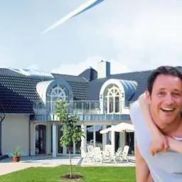 Rodzina z uśmiechem na twarzy na tle domu z oknami PCV i ogrodem