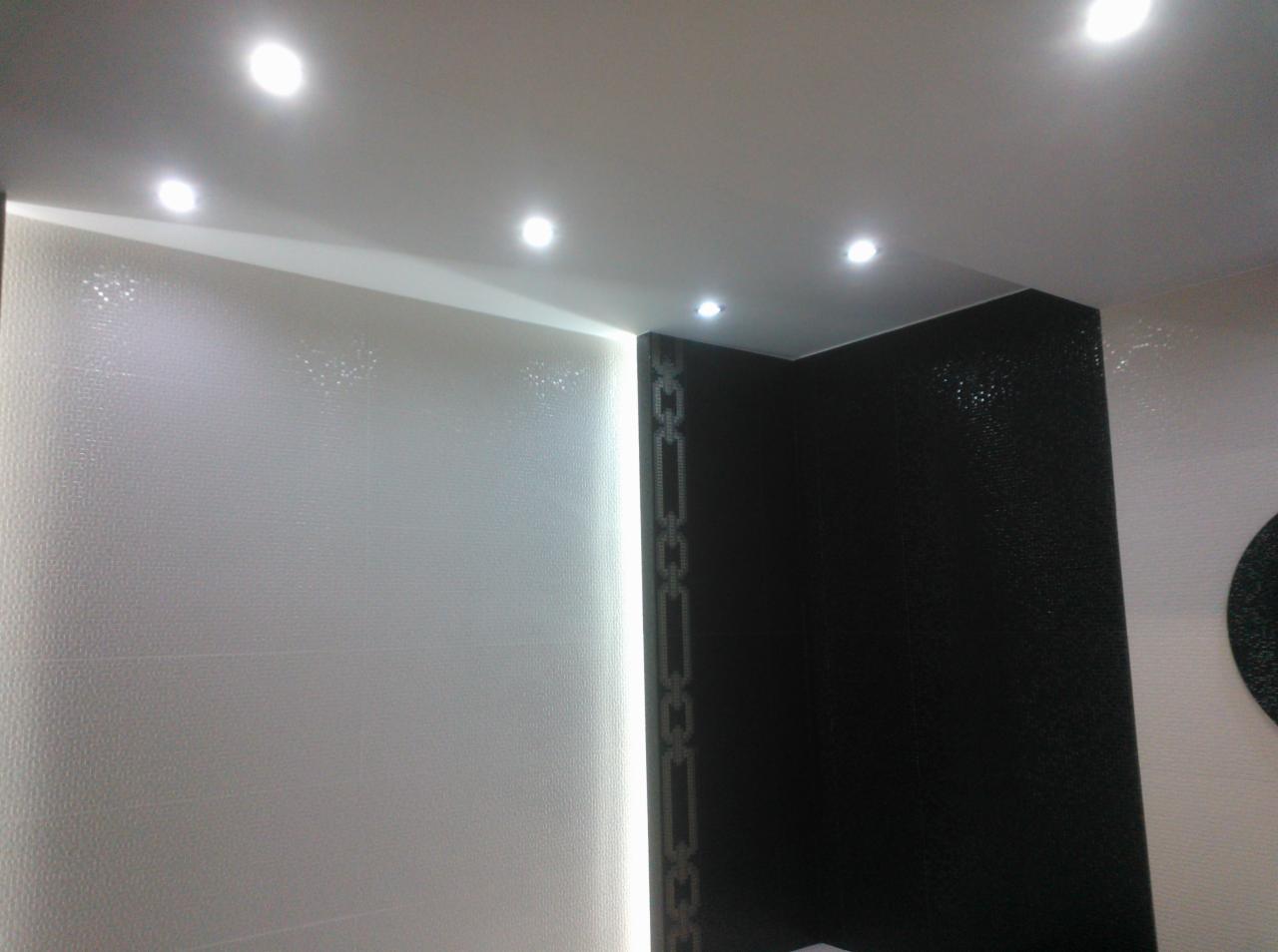 Wykończona łazienka z białymi i czarnymi płytkami, oświetleniem punktowym w suficie i pionowym pasem świetlnym.