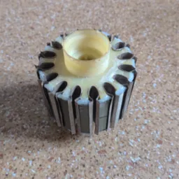 Wirnik elektronarzędzia po naprawie, z widocznymi elementami uzwojenia i izolacji, na tle blatu. Detal naprawionego elementu.