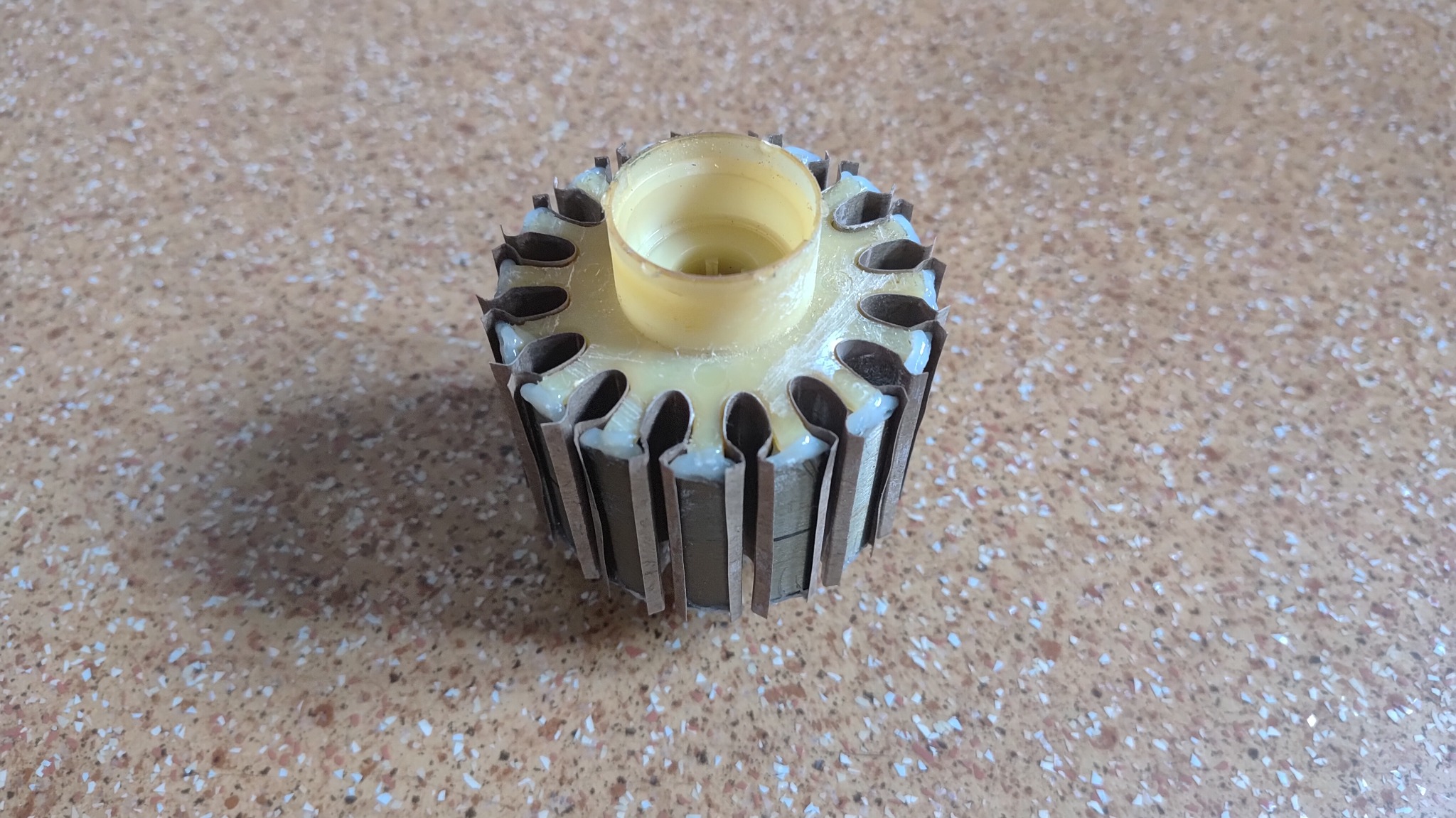 Wirnik elektronarzędzia po naprawie, z widocznymi elementami uzwojenia i izolacji, na tle blatu. Detal naprawionego elementu.