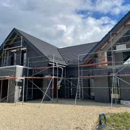 PPHU Pastenok Piotr Pasternok - Dom w trakcie budowy z czarną elewacją i grafitowym pokryciem, widoczne rusztowania i elementy konstrukcji dachu.