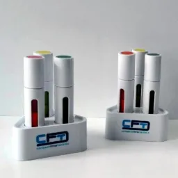 Dwa białe stojaki z logo CFT, każdy z trzema białymi cylindrami z kolorowymi wierzchołkami (czerwony, żółty, zielony) i czarnymi paskami na boku, na białym tle.